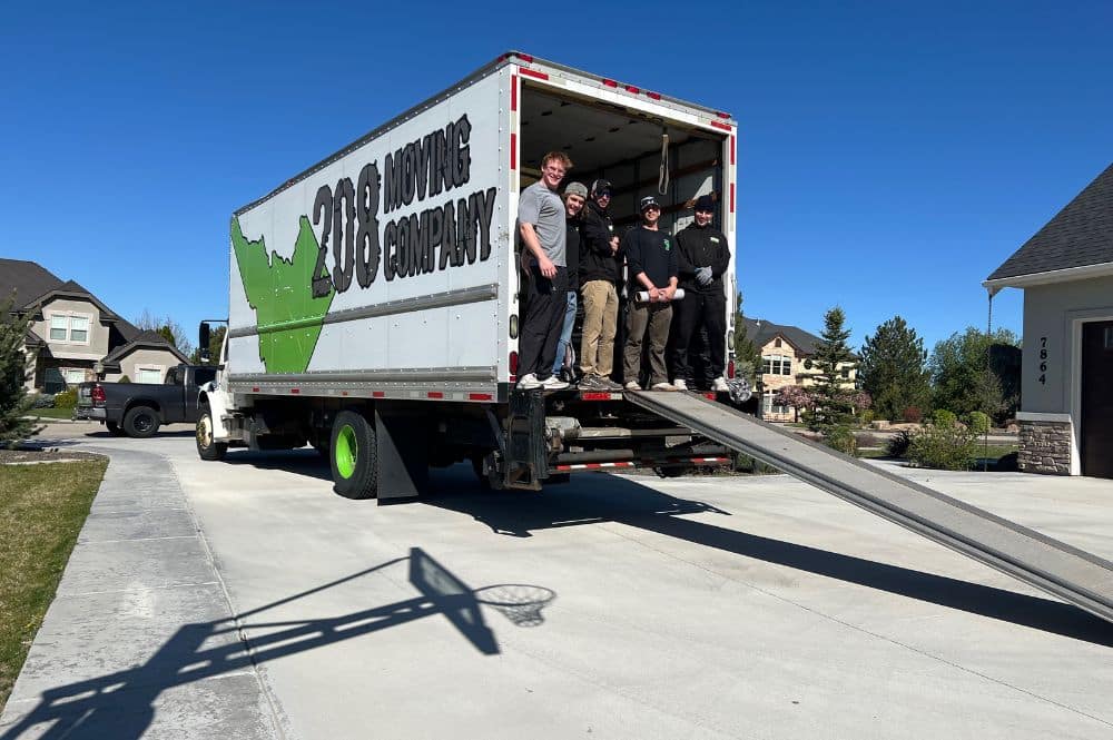 A moving team stands at the back of a moving truck in Boise, Idaho, demonstrating a professional moving service.
